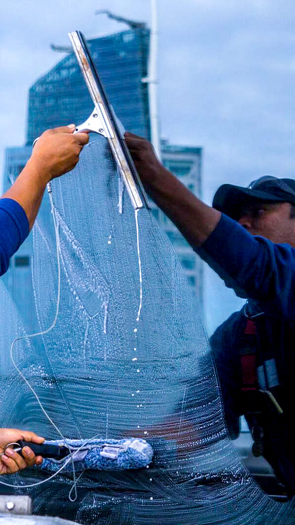 HSG technician in safety gear working on the exterior of a high-rise building, demonstrating expertise in commercial building maintenance.